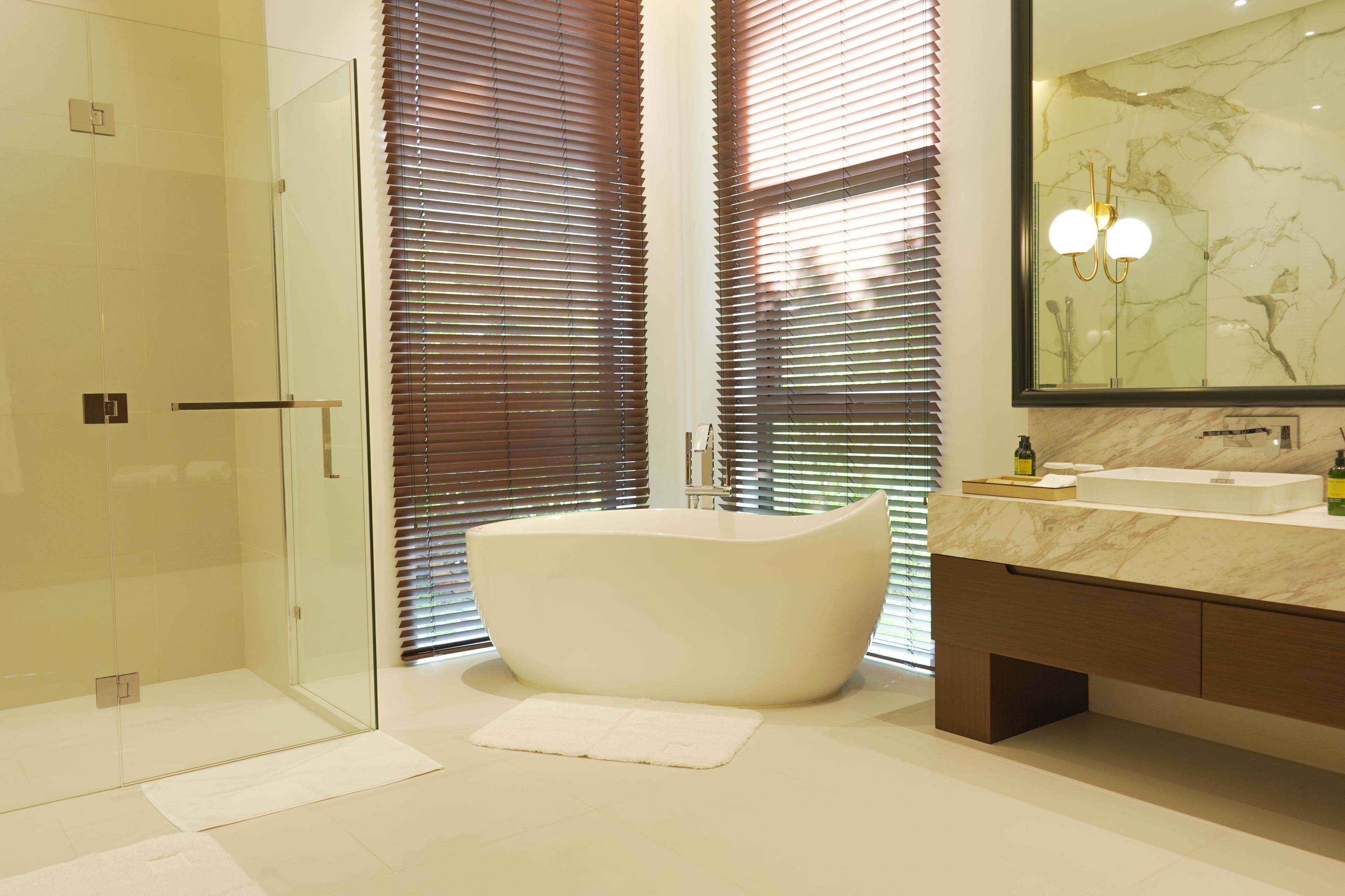 A modern bathroom with a freestanding bathtub, a glass shower enclosure, and a marble vanity.