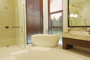 Un baño moderno con una bañera independiente, cabina de ducha con paredes de vidrio y tocador de mármol.