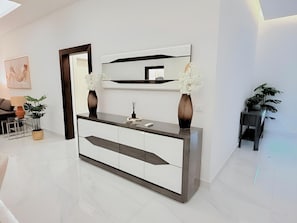 A modern living room with a white and dark grey console table, a large mirror, and a sofa. - Rooftop Pool with Riverview 3 bedroom apartment (Kinshasa)