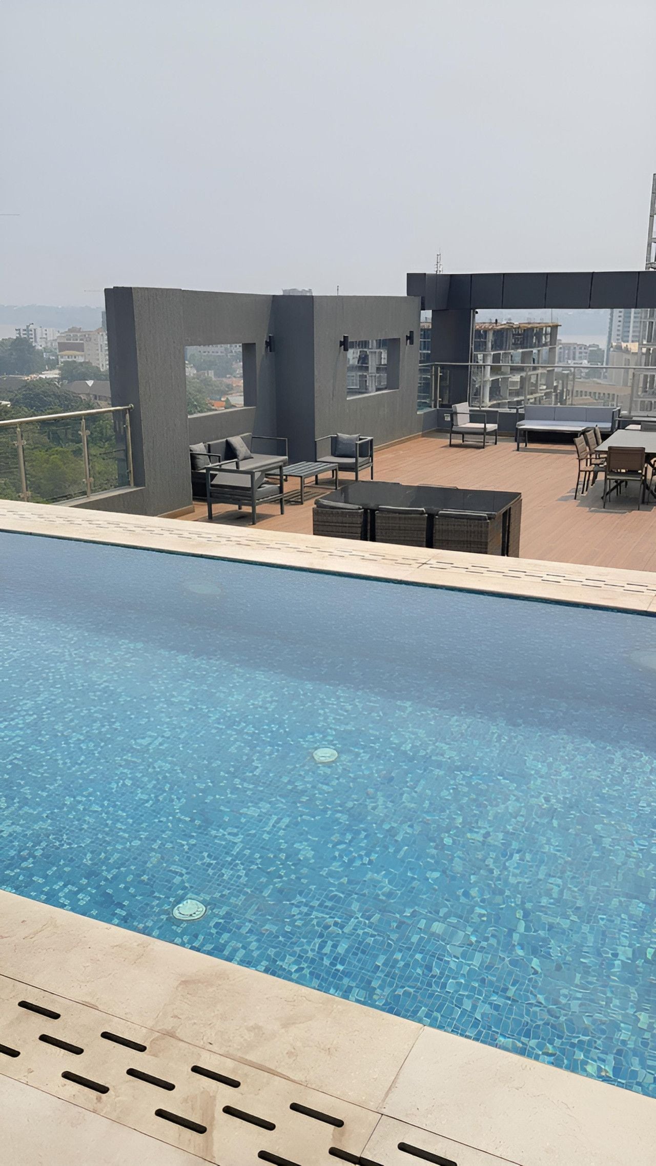 Une piscine sur le toit, avec une eau d’un bleu cristallin, entourée d’espaces de détente en plein air et offrant une vue sur le paysage urbain.