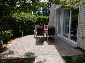 An outdoor patio with a brick floor, two chairs, and a table. - Achtern Diek 61a (Butjadingen)