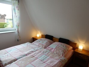 A bedroom with two beds, a window with curtains, and bedside lamps. - Achtern Diek 61a (Butjadingen)