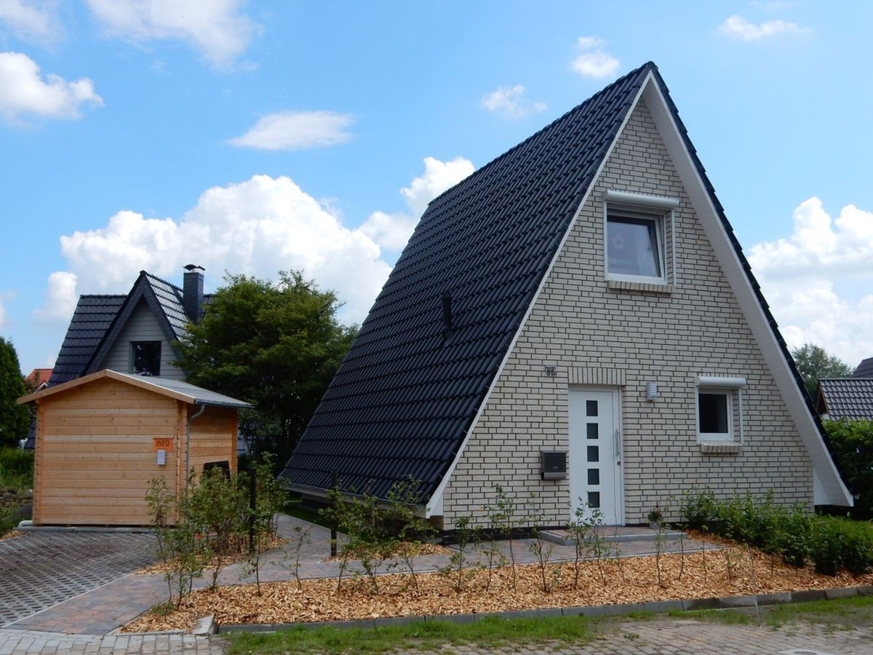 A modern house with a sloped roof, a small attached garage, and a well-maintained garden.