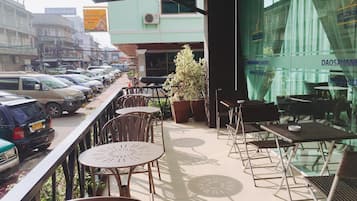 A balcony with outdoor seating, a view of parked cars, and a building with signage.