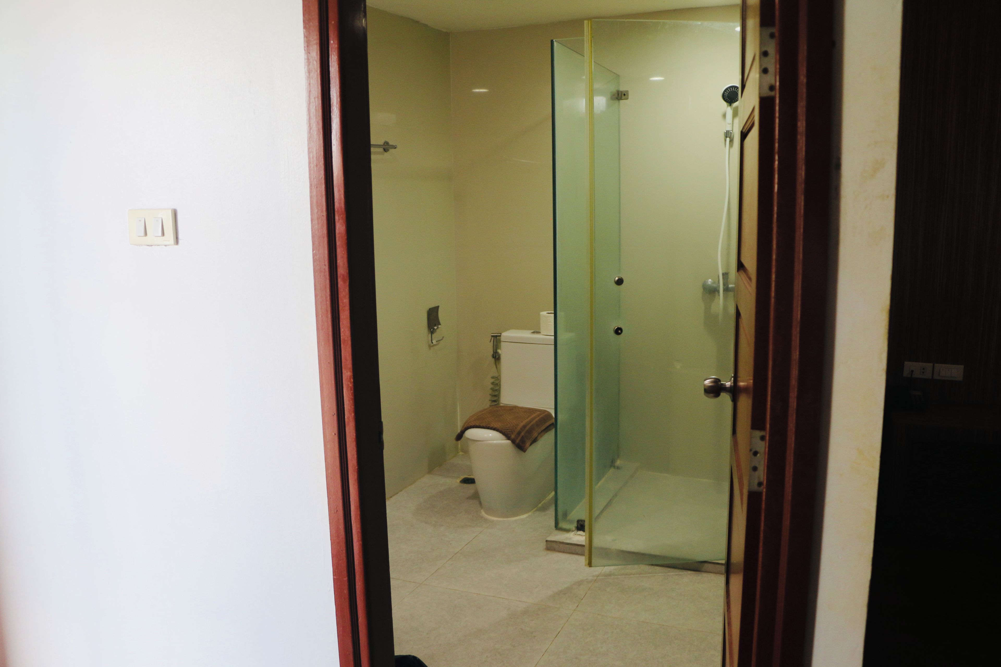 Een badkamer met een douchecabine van glas, toilet en een prullenbak.