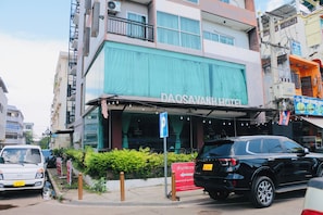 Un edifici amb un rètol de DAOSAVAN HOTEL, amb un balcó amb llums de garlandes i una tenda verda.