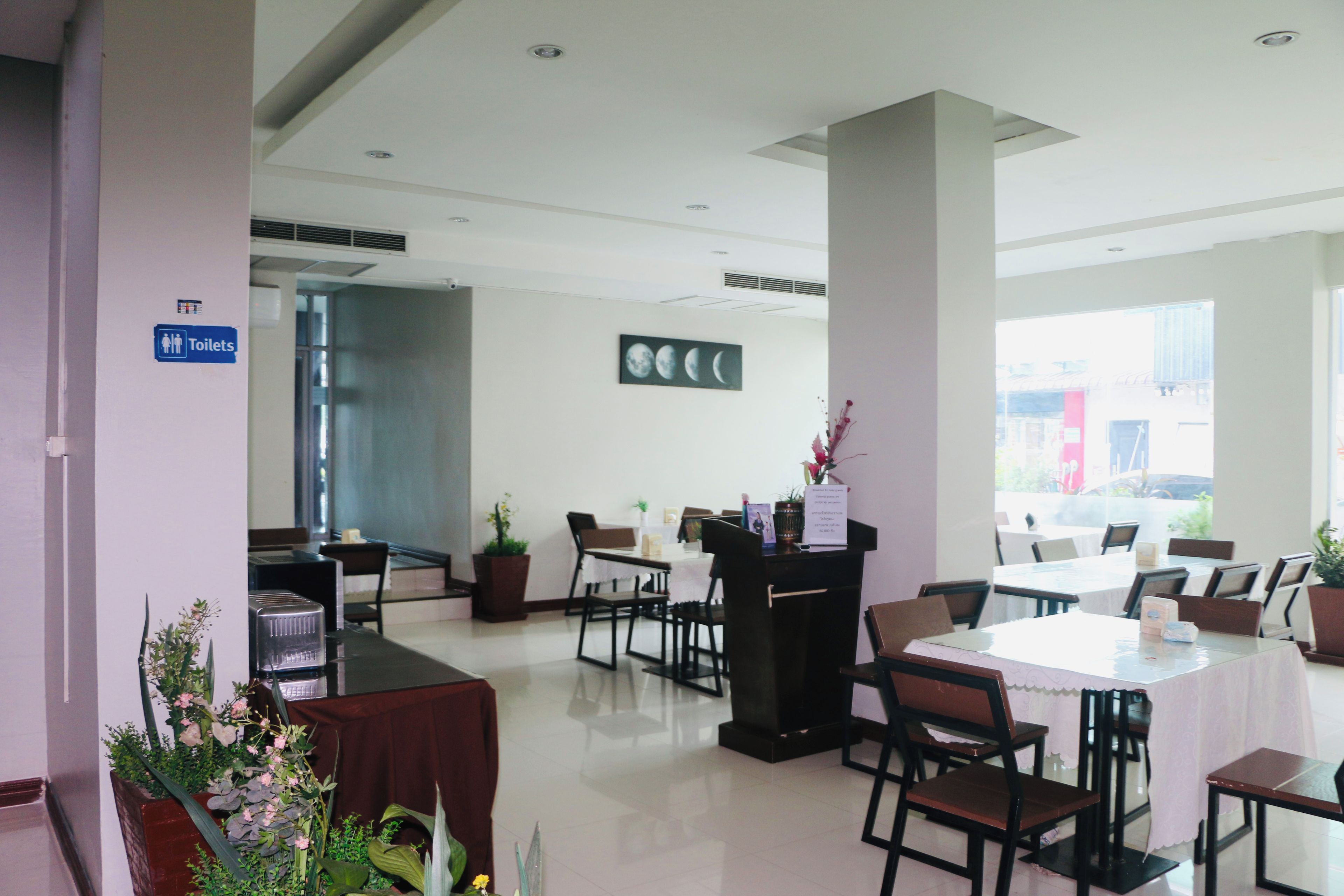 A hotel lobby with a reception desk, seating area, and a sign indicating the location of toilets.