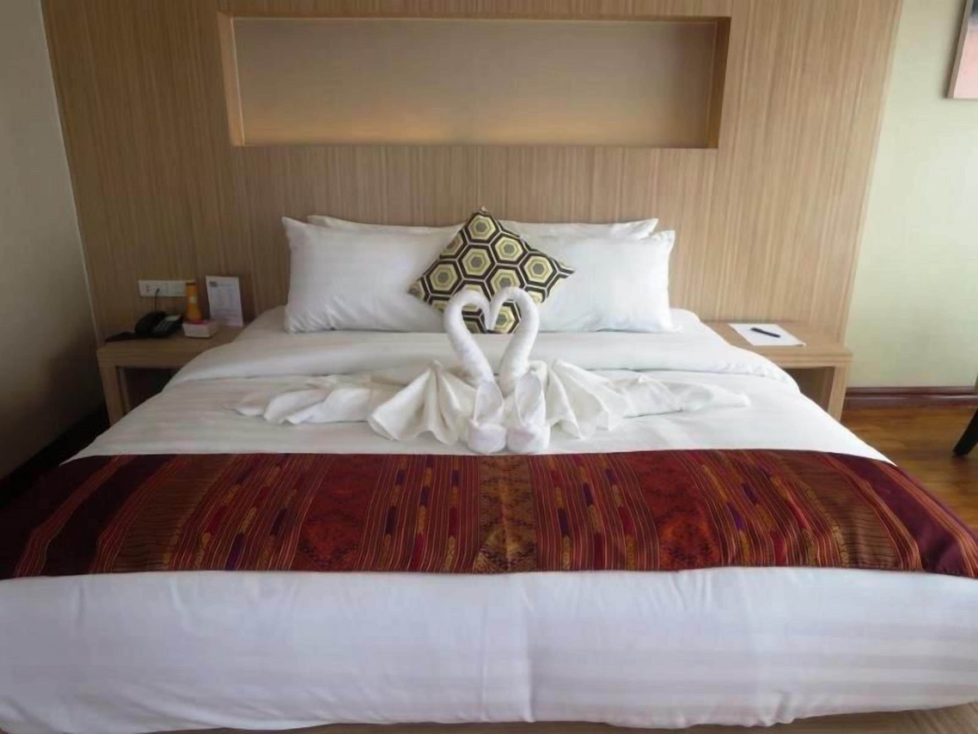 Una habitación de hotel con una cama, una mesita de noche y una estantería en la pared.
