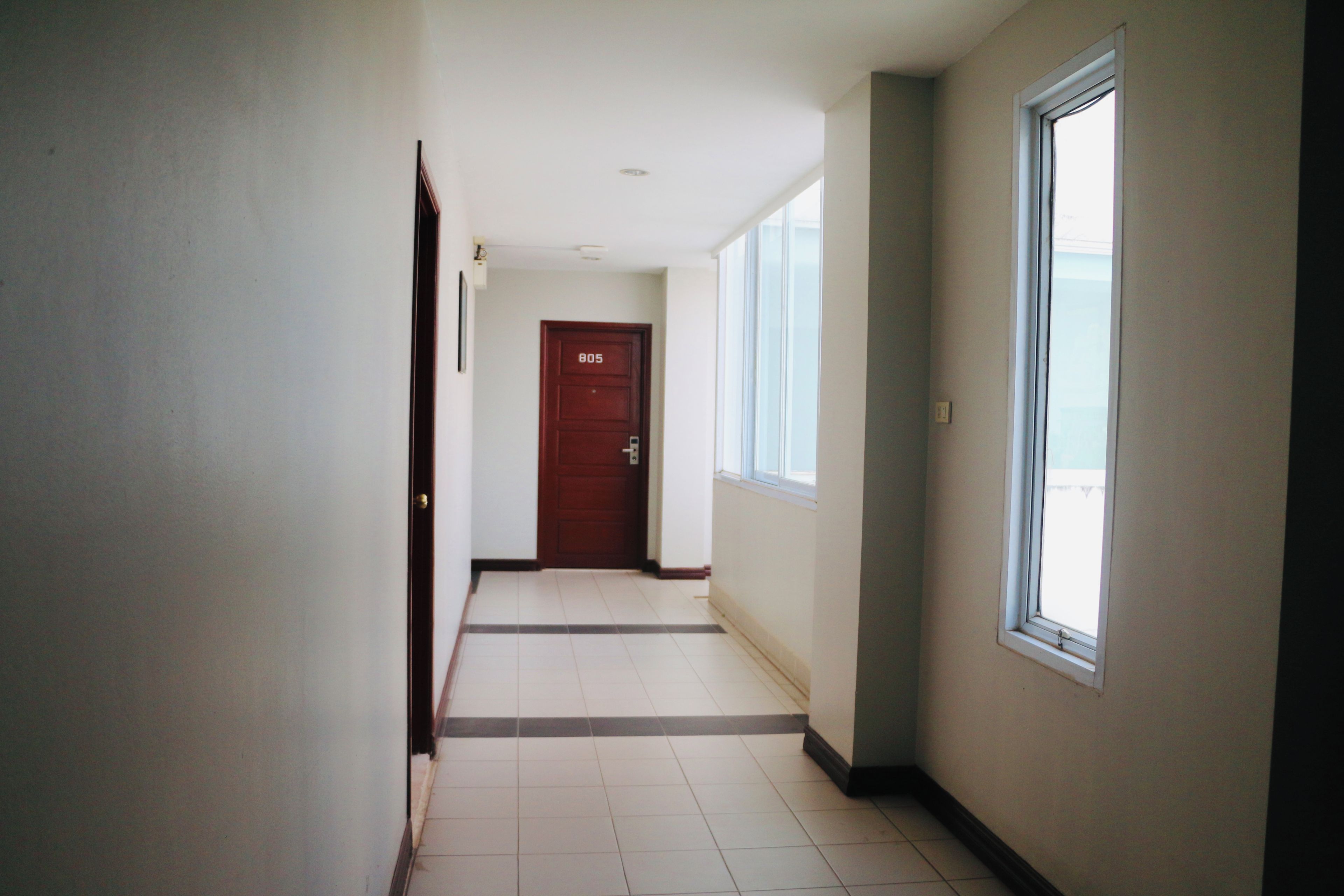 A hallway with a door marked 805, a window, and a tiled floor.