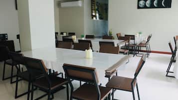 Un comedor con una mesa larga y sillas, techo blanco y un cuadro colgado en la pared.