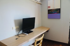 Habitació amb escriptori de fusta, monitor negre i una cadira.
