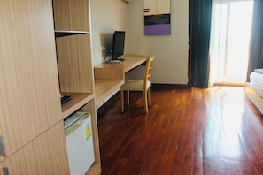 Una habitació amb escriptori de fusta, cadira, televisió i llit.