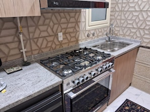 A kitchen with a gas stove, oven, and a sink. - 15 Bustan Downtown 
Timeless class, modern comfort (Cairo Governorate)