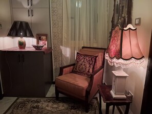A room with a wooden cabinet, a cushioned chair, a patterned rug, and a table with a lamp. - 15 Bustan Downtown 
Timeless class, modern comfort (Cairo Governorate)