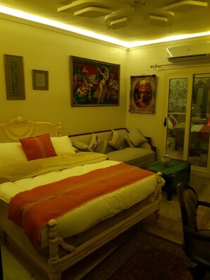 A bedroom with a bed, a chair, a table, and two paintings on the wall. - 15 Bustan Downtown 
Timeless class, modern comfort (Cairo Governorate)