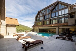 Un edifici modern amb piscina, zona de seients a l'aire lliure i vistes a un turó.