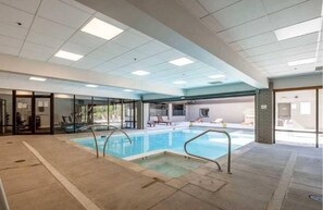 An indoor swimming pool with clear glass walls, a tiled floor, and a ceiling with recessed lighting. - Lodge at Mtn Village A303 | Ski-In/Ski-Out | PCMR Base | Pool | Hot Tub | Mtn Views | Fireplace (Park City)