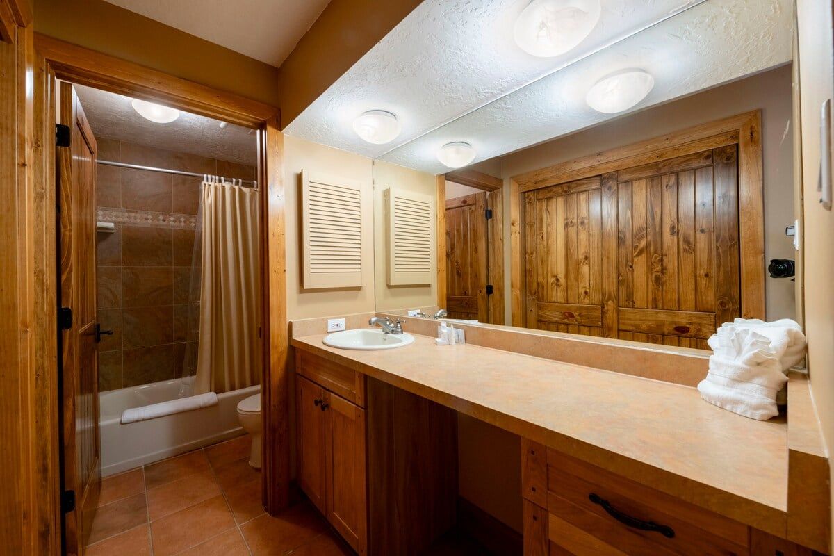 A bathroom with a wooden vanity, a bathtub, a shower, and a large mirror.