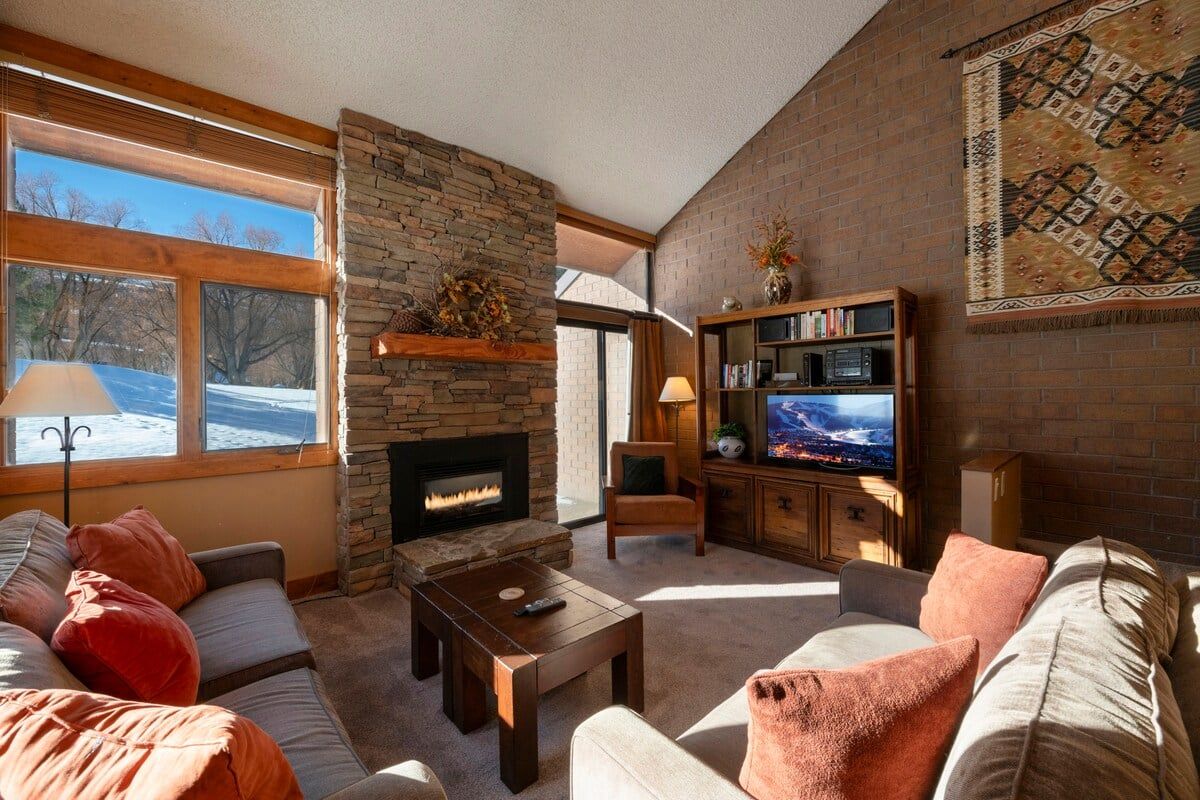 A cozy living room with a fireplace, comfortable seating, and a bookshelf.
