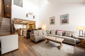 A spacious living area with a sofa set, a coffee table, and a staircase leading to an upper level. - Park Ave 216 | Heated Pool | Hot Tub | ¼ Mile to PCMR | Next to Golf Course | Walk to Shops (Park City)