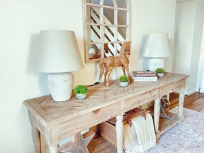 A wooden console table with two lamps, a horse sculpture, and small potted plants. - There’s lots to love here. (Kelso)