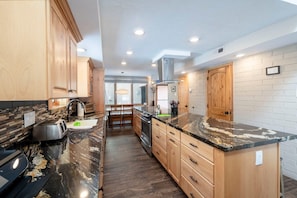 A modern kitchen with wooden cabinets, a marble countertop, and a central island. - Park Ave 235 | Heated Pool | Hot Tub | Remodeled | Stone Fireplace | Granite Kitchen | Laundry (Park City)
