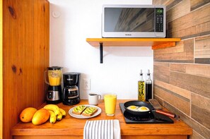 A kitchen with a microwave, coffee maker, blender, and a breakfast setup including toast, eggs, and juice. - Easy Mornings. 5th Ave, ADO, Cozumel Ferry & Beach 4 Mins · Memory Foam King Bed (Playa del Carmen)