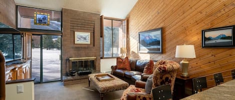 Una sala de estar acogedora con chimenea, sofá de cuero y una zona de comedor con sillas.