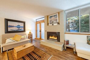 A living room with a fireplace, a sofa, a coffee table, and a rug. - Park Ave 297 | Heated Pool | Hot Tub | No Stairs | Private Patio & Grill | Fireplace | Free Bus (Park City)