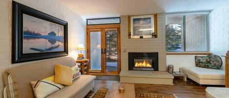 A living room with a fireplace, a sofa, a coffee table, and a rug.