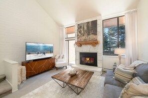 Ein Wohnzimmer mit Kamin, Fernseher und einer Couch.