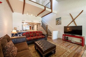 A living room with a sofa, ottoman, and a television on a stand. - Park Ave 333 | Heated Pool | Hot Tub | Fireplace | A/C | Patio & Grill | Near PCMR | Free Bus (Park City)