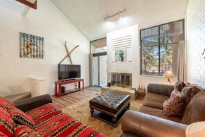 A living room with a fireplace, a television, and a patterned sofa. - Park Ave 333 | Heated Pool | Hot Tub | Fireplace | A/C | Patio & Grill | Near PCMR | Free Bus (Park City)