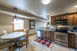 A kitchen with wooden cabinets, a stainless steel oven, and a microwave. - Jupiter Inn 10 | Community Hot Tub | Gas Fireplace | A/C | Laundry | Walk to Dining | Free Bus (Park City)
