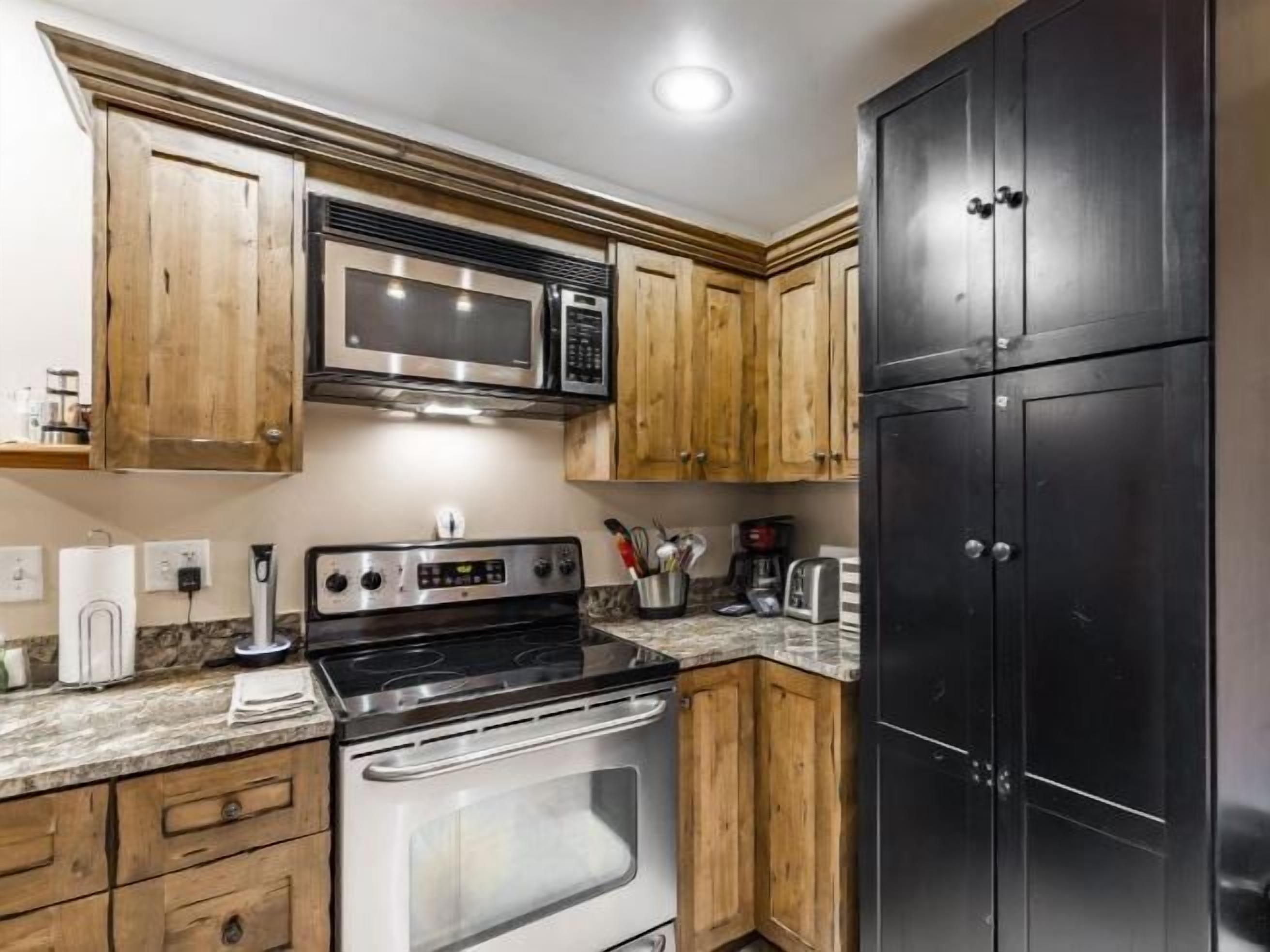 The kitchen at Jupiter Inn 18 features granite countertops, warm wood cabinetry, and modern appliances, giving you everything you need for a comfortable and convenient Park City vacation rental stay.