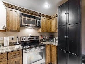 The kitchen at Jupiter Inn 18 features granite countertops, warm wood cabinetry, and modern appliances, giving you everything you need for a comfortable and convenient Park City vacation rental stay. - Jupiter Inn 18 | Mtn View Balcony | 2 Living Areas | Fireplace | Hot Tub | A/C | Free Bus (Park City)