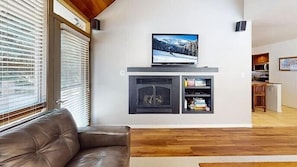 A living room with a fireplace, a television, and a leather sofa. - Payday 189 | Walk to Silver Star Lift | Private Hot Tub | Renovated | Vaulted Cedar Ceilings | A/C (Park City)