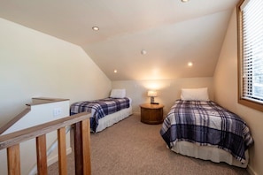 A bedroom with two beds, a wooden staircase, a lamp, and a window. - Payday 189 | Walk to Silver Star Lift | Private Hot Tub | Renovated | Vaulted Cedar Ceilings | A/C (Park City)