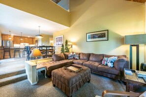 A living room with a sectional sofa, a coffee table, and a dining area in the background. - Payday 183 | Walk to Silver Star Lift | Private Hot Tub | Vaulted Cedar Ceilings | Mtn Views (Park City)