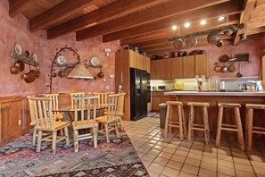 Eine rustikale Küche mit Holmöbeln, einem Kühlschrank und hängenden Töpfen.