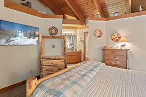 Ein Schlafzimmer mit einem Bett, einer Holzkommode und einem Spiegel.