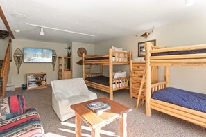 Ein Zimmer mit Etagenbetten, einem weißen Sofa, einem kleinen Tisch und einem Bild an der Wand.