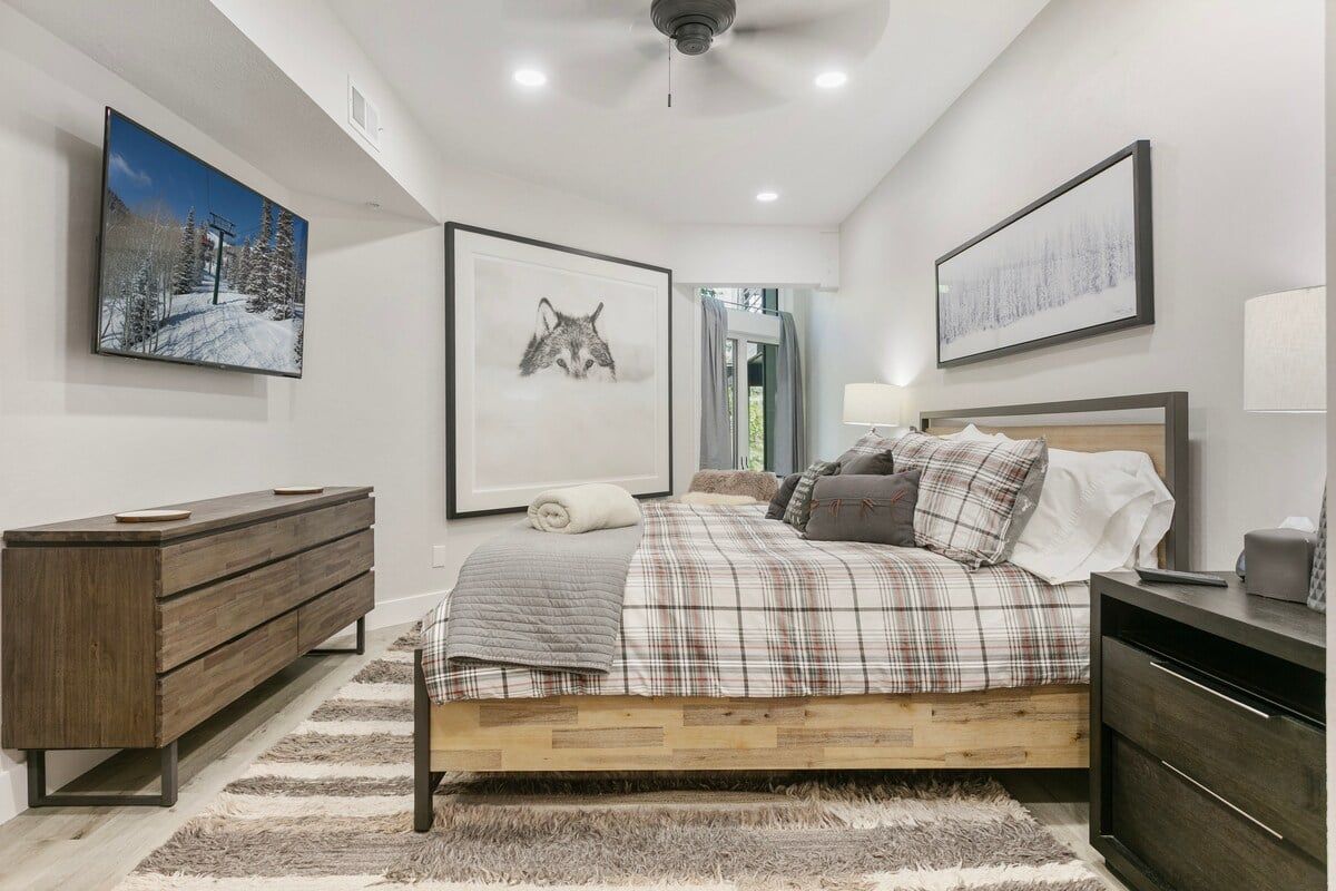 A bedroom with a bed, a dresser, a nightstand, a lamp, and framed pictures on the walls.