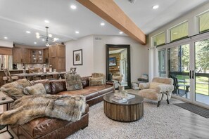 A modern living room with a brown leather sofa, a round coffee table, and a fluffy armchair.