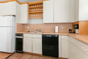 A kitchen with white cabinets, a dishwasher, a sink, and a coffee maker. - Three Kings 41 | Walk to Three Kings Lift | Heated Pool | Hot Tub | Sauna | Updated | Free Bus (Park City)