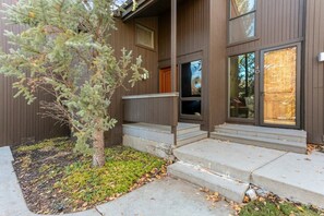 A modern two-story building with a wooden exterior, a small tree in the front yard, and a set of concrete steps leading to the entrance. - Three Kings 41 | Walk to Three Kings Lift | Heated Pool | Hot Tub | Sauna | Updated | Free Bus (Park City)