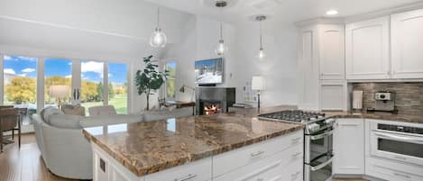 Una cocina moderna con armarios blancos, encimera de granito y estufa integrada.