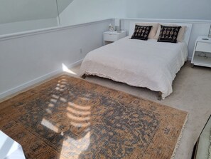 Une chambre à coucher avec un grand lit, deux tables de chevet et un tapis à motifs.