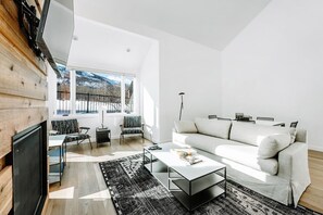 A modern living room with a white sofa, a coffee table, and a patterned rug. - Three Kings 80 | Walk to Three Kings Lift | Heated Pool | Hot Tub | Remodeled | Original Artwork (Park City)