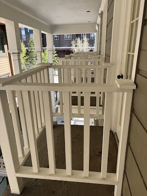 Ein weißer Holzbalkon mit Blick auf benachbarte Gebäude und Bäume.
